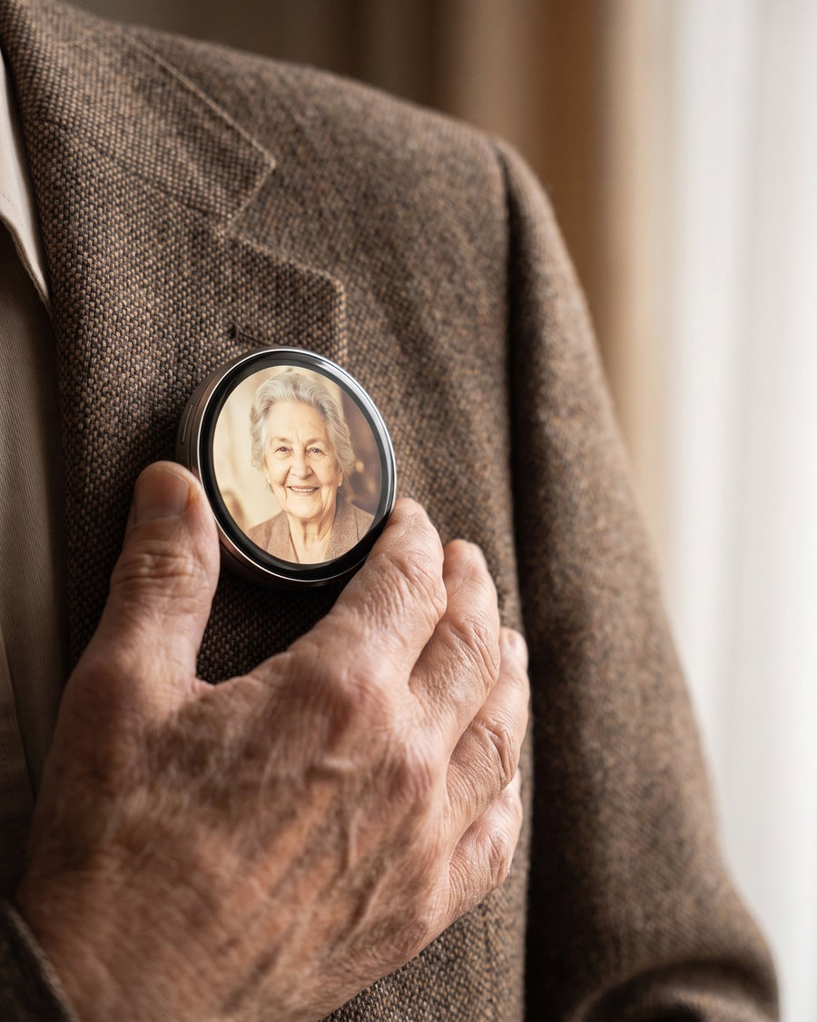 Older man's hand near a Lumipin on his tweed lapel showing a vintage photo of a woman.