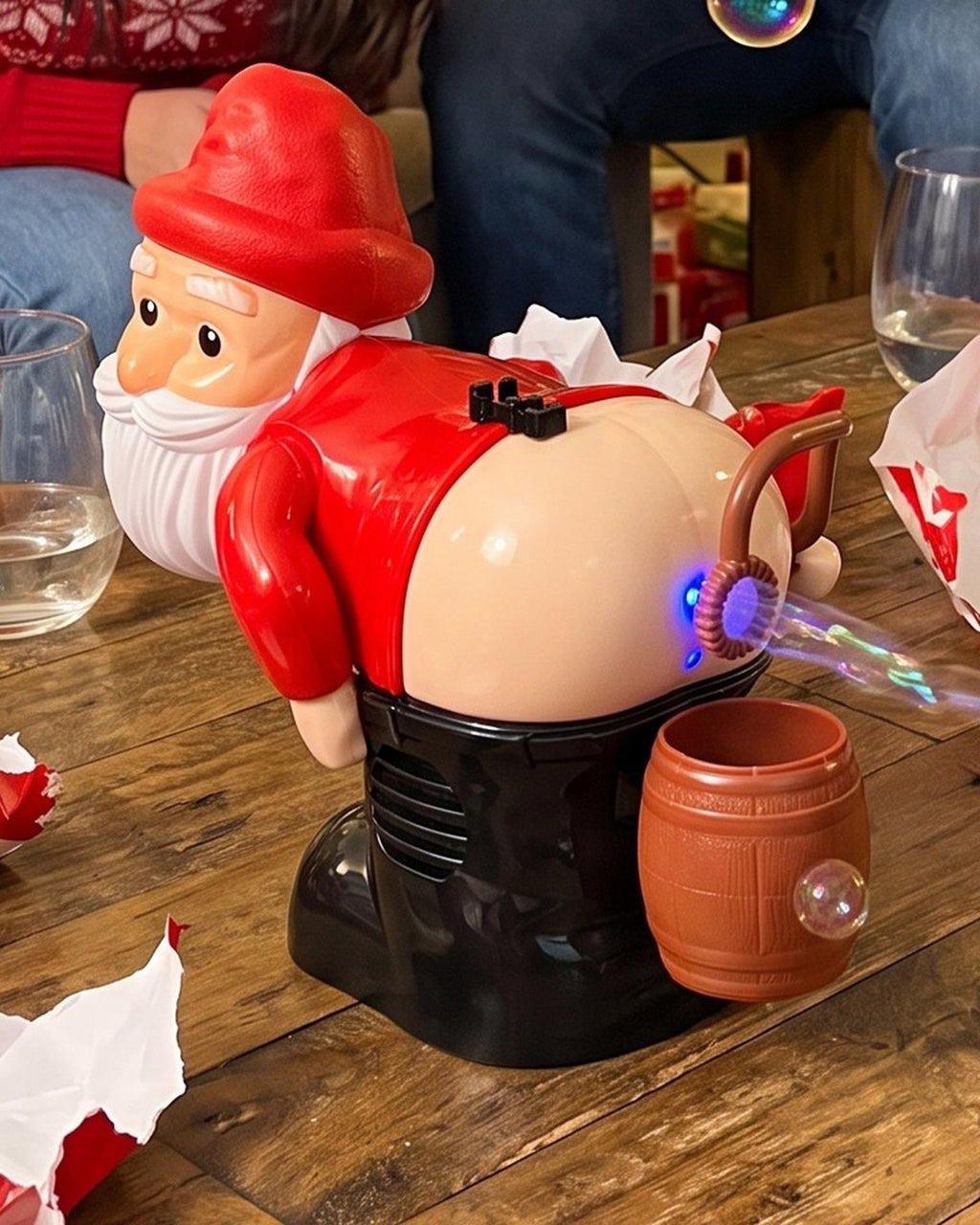 Farting Santa bubble machine on a party table, a stream of bubbles coming out of the glowing blue ring on his bum.